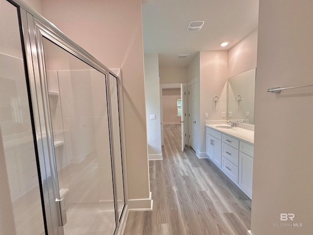 bathroom with hardwood / wood-style floors, vanity, and a shower with door