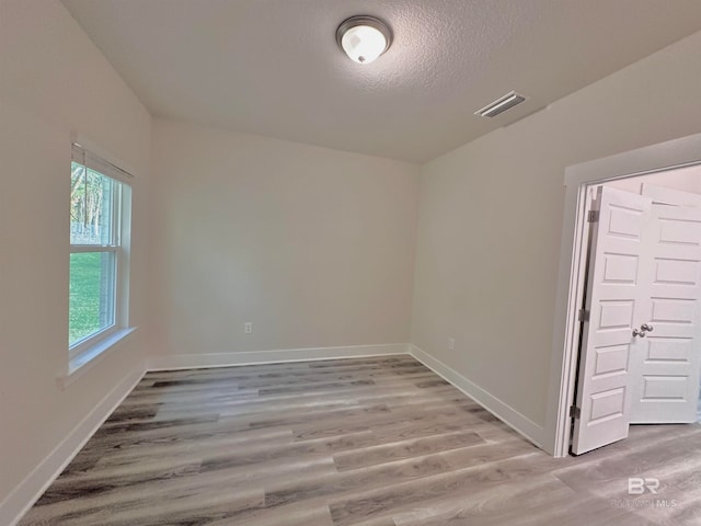 spare room with light hardwood / wood-style floors and a textured ceiling