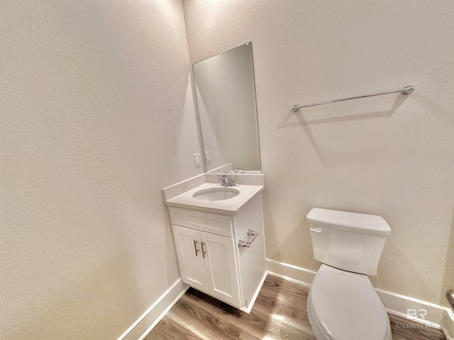 bathroom with toilet, vanity, and hardwood / wood-style floors