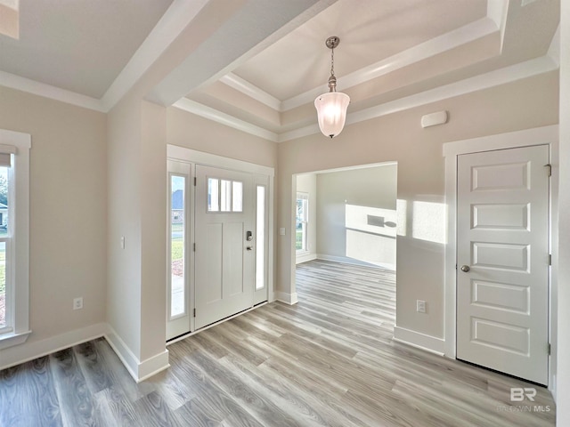 entrance foyer featuring light wood-type flooring, a tray ceiling, and crown molding