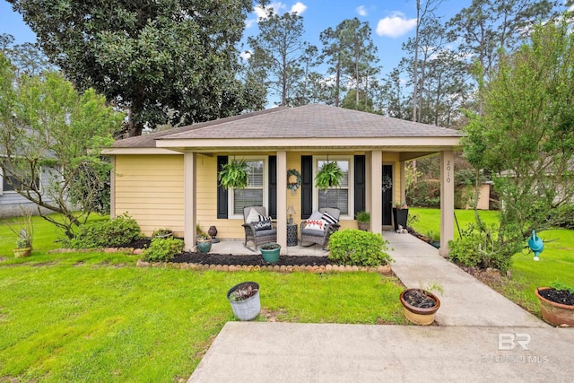 view of front of home with a shingled roof, a front lawn, and a patio area