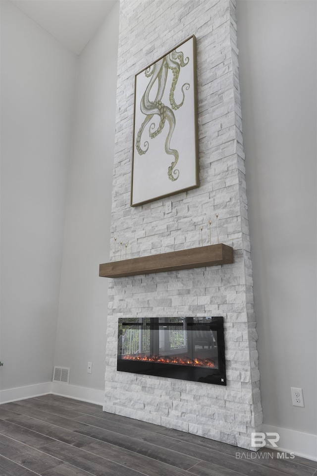 interior details featuring visible vents, a stone fireplace, wood finished floors, and baseboards