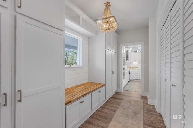 mudroom featuring dark wood-style flooring, baseboards, and a notable chandelier