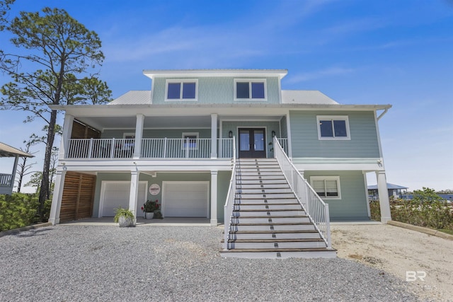 beach home featuring french doors, metal roof, gravel driveway, and stairway
