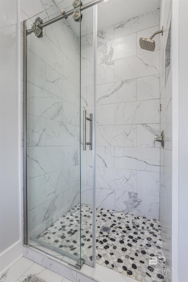 bathroom with marble finish floor and a stall shower