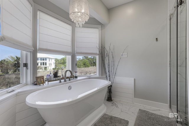 bathroom featuring a notable chandelier, marble finish floor, a freestanding tub, and a shower with door