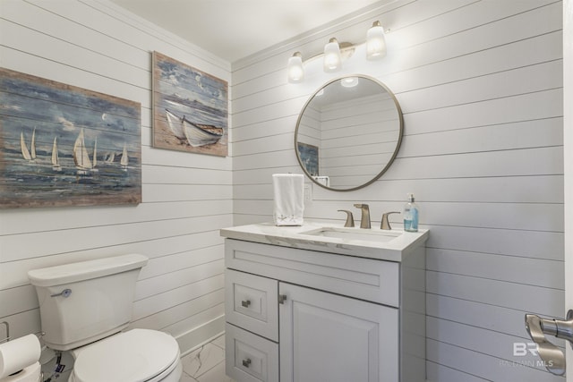 bathroom featuring wood walls, vanity, marble finish floor, and toilet