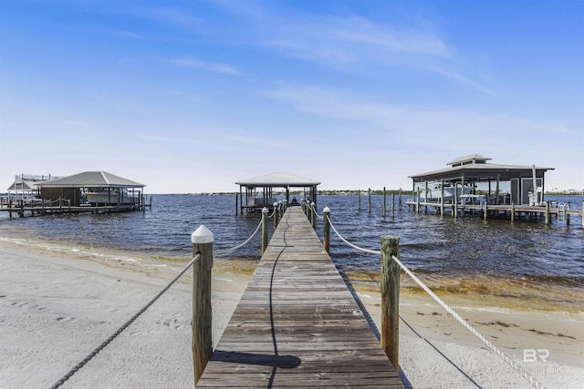 dock area featuring boat lift, a view of the beach, and a water view