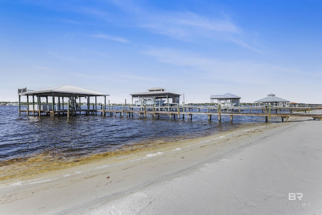 dock area featuring a view of the beach, boat lift, and a water view
