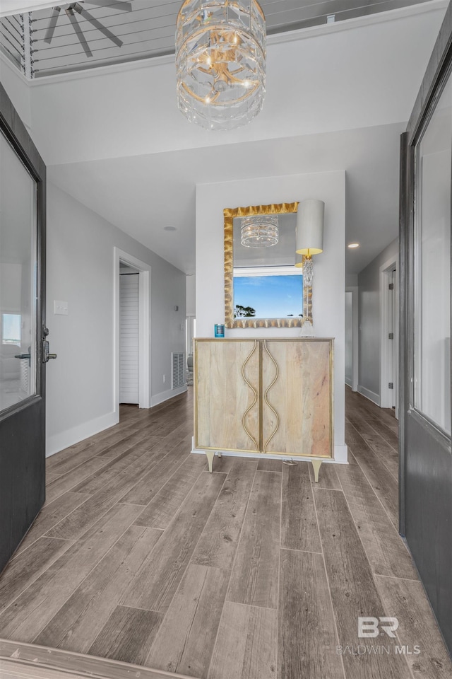 interior space featuring visible vents, baseboards, a ceiling fan, and wood finished floors