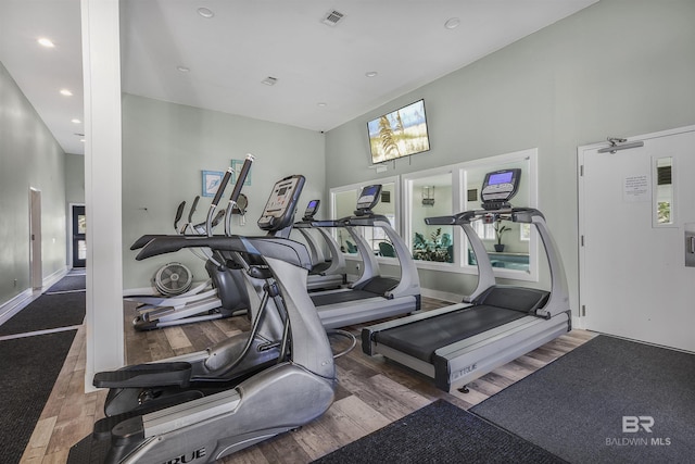 workout area featuring wood finished floors, a towering ceiling, visible vents, and recessed lighting