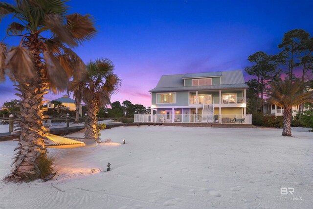 back of property at dusk with a porch and metal roof