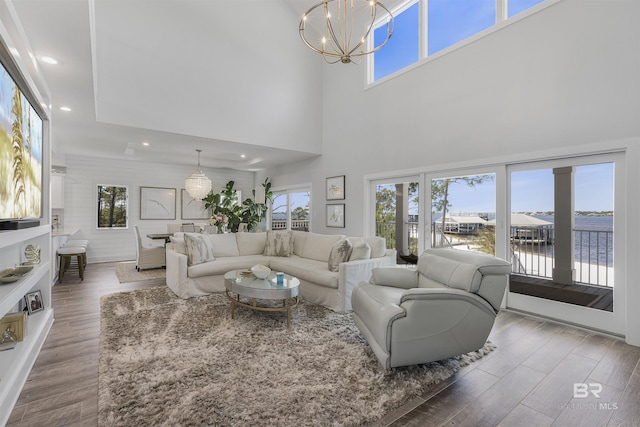 living room with a water view, recessed lighting, an inviting chandelier, and wood finished floors
