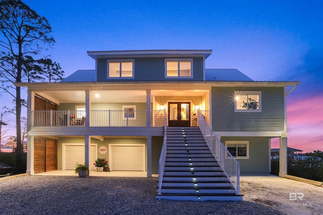 coastal inspired home with stairway, metal roof, driveway, and covered porch