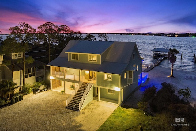 rear view of house with driveway, a water view, and stairs