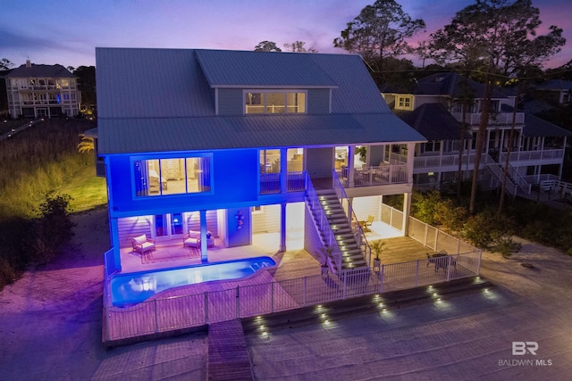 exterior space with a swimming pool, a patio area, stairs, metal roof, and fence