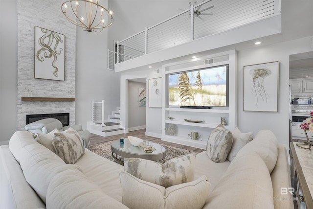 living area with baseboards, a high ceiling, a fireplace, stairway, and wood finished floors