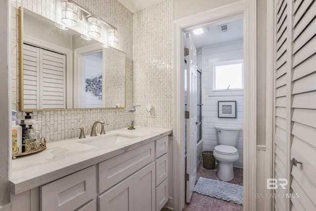 full bathroom featuring toilet, tile walls, vanity, backsplash, and tile patterned floors
