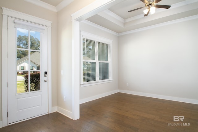 foyer entrance featuring dark wood-type flooring, baseboards, a raised ceiling, and ornamental molding