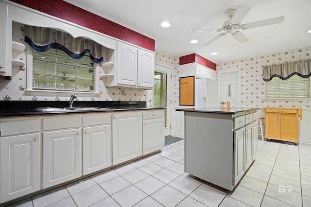 517 Simms Dr, Saraland, AL 36571 - kitchen with wallpapered walls, dark countertops, light tile patterned flooring, and white cabinetry