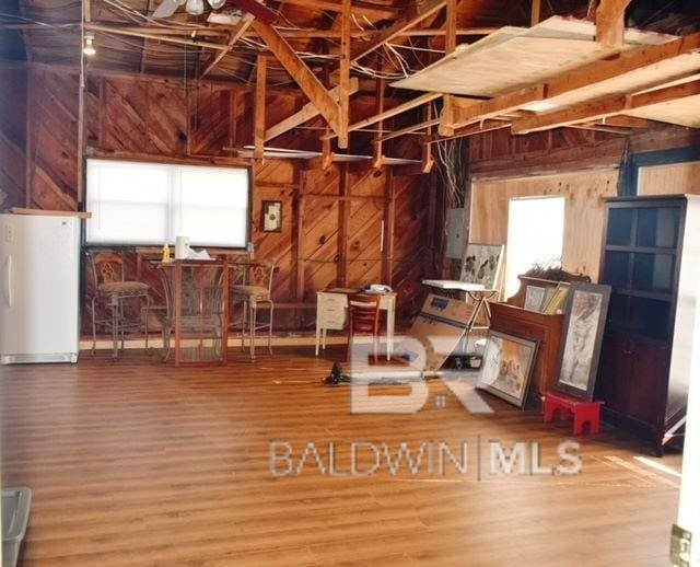 misc room featuring wood walls, wood-type flooring, and electric panel