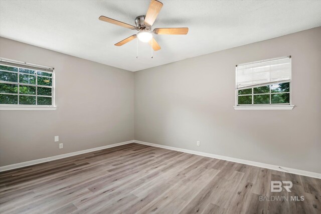 unfurnished room featuring ceiling fan, plenty of natural light, and light hardwood / wood-style flooring