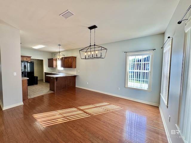 kitchen with black refrigerator, sink, pendant lighting, light hardwood / wood-style floors, and a kitchen island