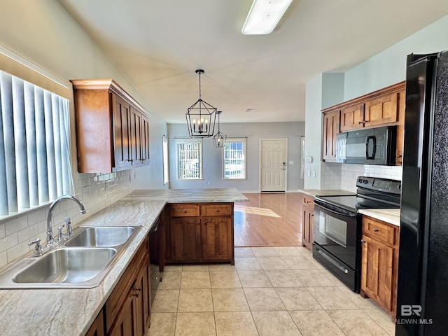 kitchen with sink, a notable chandelier, kitchen peninsula, decorative light fixtures, and black appliances