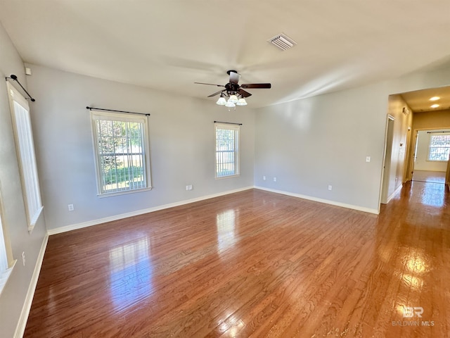 spare room featuring ceiling fan, a barn door, and wood-type flooring