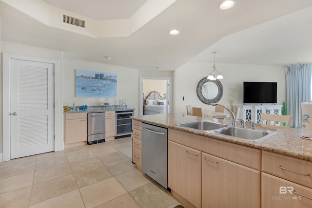 kitchen featuring light brown cabinetry, stainless steel dishwasher, beverage cooler, sink, and pendant lighting