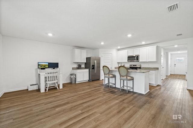 1149 Hayward Loop, Foley, AL 36535 - kitchen featuring appliances with stainless steel finishes, light wood-style flooring, white cabinetry, a kitchen bar, and recessed lighting