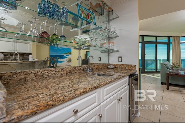 bar with beverage cooler, ornamental molding, light tile patterned floors, wet bar, and a sink
