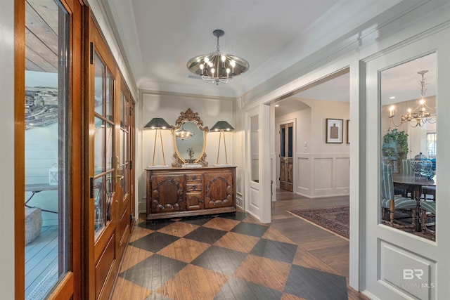 hallway with ornamental molding and a notable chandelier