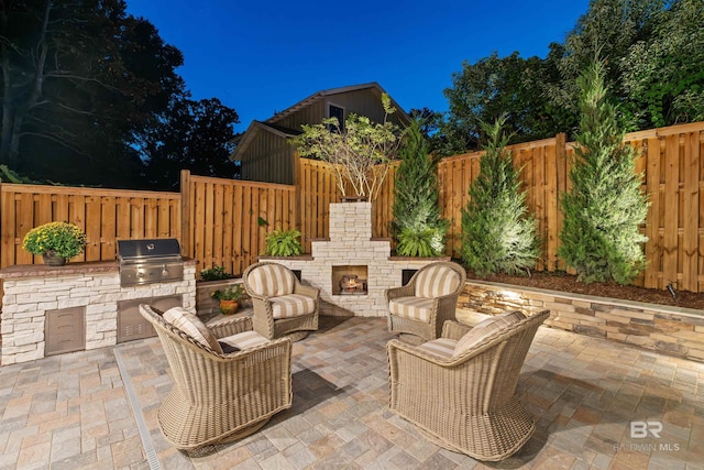 view of patio featuring exterior kitchen, area for grilling, and an outdoor stone fireplace