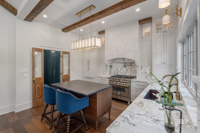 kitchen featuring beamed ceiling, light stone countertops, pendant lighting, double oven range, and dark hardwood / wood-style flooring