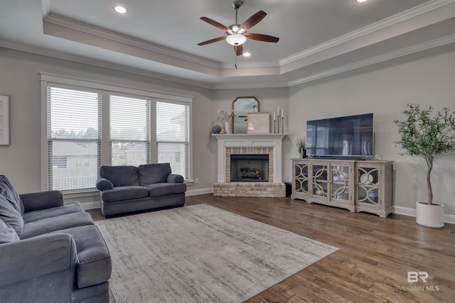 12708 Ibis Blvd, Spanish Fort, AL 36527 - living room featuring a ceiling fan, a raised ceiling, wood finished floors, ornamental molding, and a brick fireplace