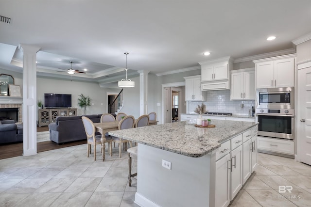12708 Ibis Blvd, Spanish Fort, AL 36527 - kitchen with stainless steel appliances, ornamental molding, open floor plan, white cabinets, and a center island