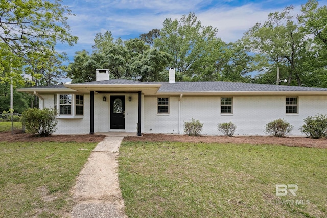 single story home featuring a chimney, brick siding, fence, and a front yard