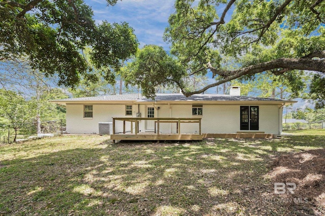 rear view of house featuring fence, central air condition unit, a chimney, and brick siding