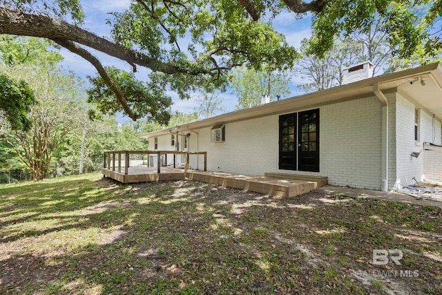 back of house with brick siding, a wooden deck, and a chimney