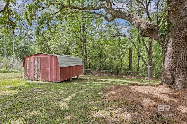 view of yard with an outdoor structure, a fenced backyard, a storage shed, and a forest view
