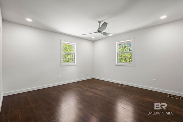 empty room featuring ceiling fan, visible vents, baseboards, and wood finished floors