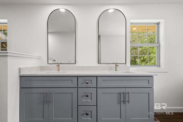 bathroom with double vanity, baseboards, a sink, and wood finished floors