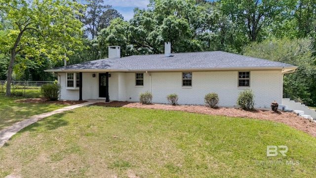 ranch-style house featuring fence, a chimney, brick siding, and a front yard