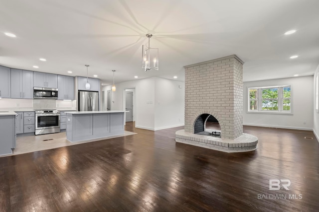unfurnished living room with a brick fireplace, recessed lighting, baseboards, and wood finished floors