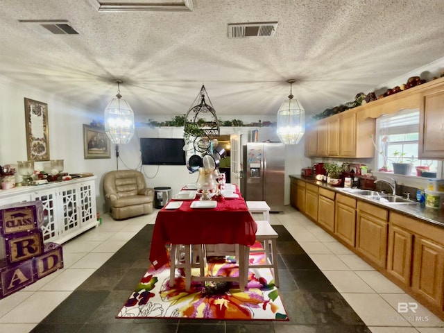 kitchen featuring a sink, stainless steel fridge, a chandelier, decorative light fixtures, and a textured ceiling