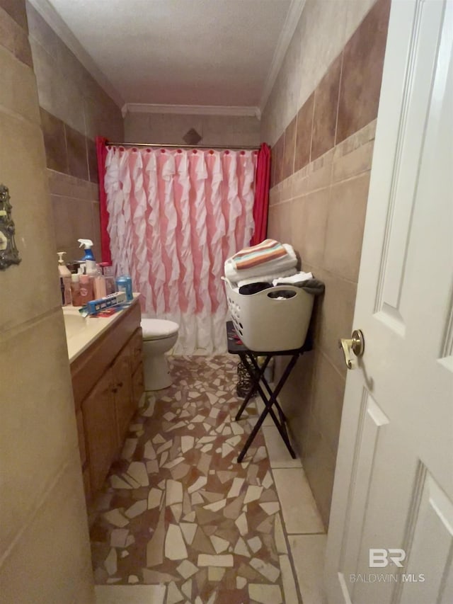 bathroom with tile walls, crown molding, toilet, vanity, and a shower with shower curtain