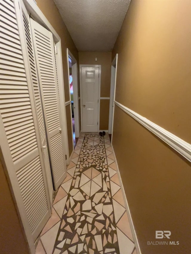hall with light tile patterned flooring and a textured ceiling