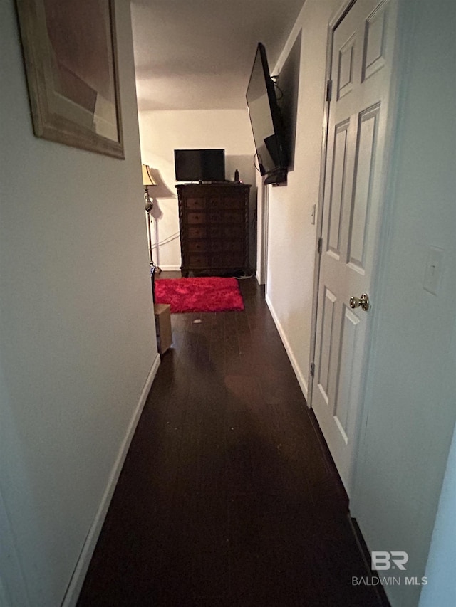 hall featuring baseboards and dark wood-style flooring
