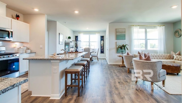 138 Preston Way, Gulf Shores, AL 36542 - kitchen with stainless steel appliances, white cabinets, a kitchen breakfast bar, light stone counters, and recessed lighting